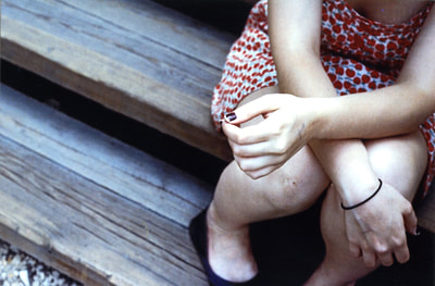 colour film photo of girl's arms and legs on wooden stairs