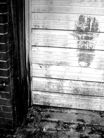 black and white photo of weathered footprint on an old wooden garage door