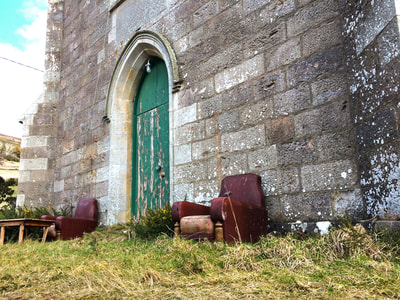 landscape colour photo of church with weathered red leather sofas out front